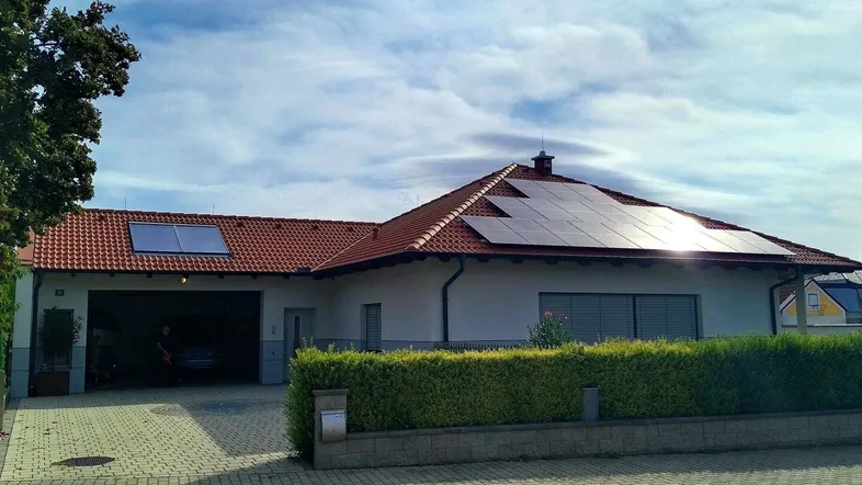 Einfamilienhaus mit Satteldach, Photovoltaikanlage und gepflegter Hecke im Vorgarten.