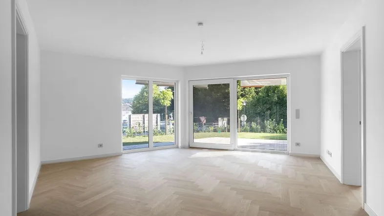Helles Wohnzimmer mit Fischgrätparkett und großen Schiebetüren zum Gartenbereich.