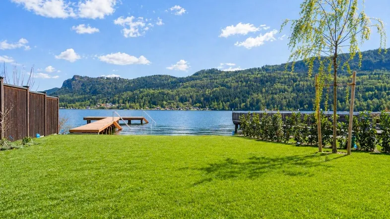 Gepflegte Rasenfläche mit direktem Zugang zum See und malerischem Blick auf die umliegenden Berge.