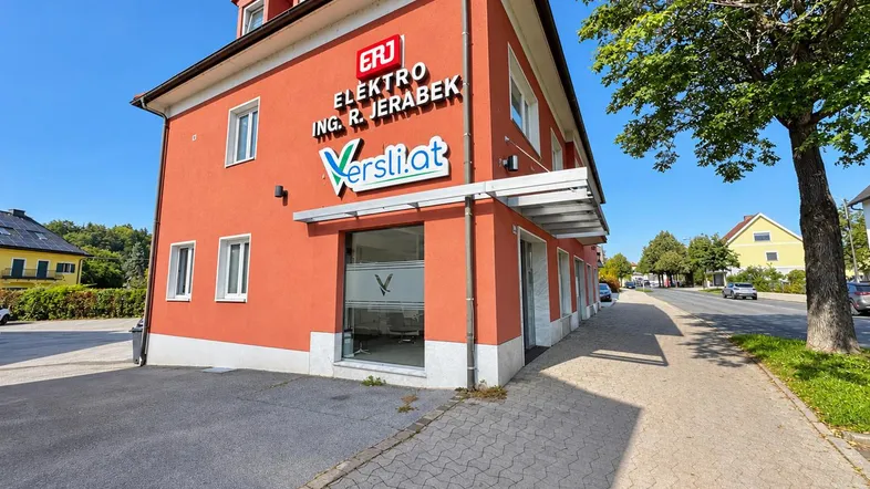 Gebäude mit orangeroter Fassade und Geschäftsaufschrift an einer Straße gelegen.