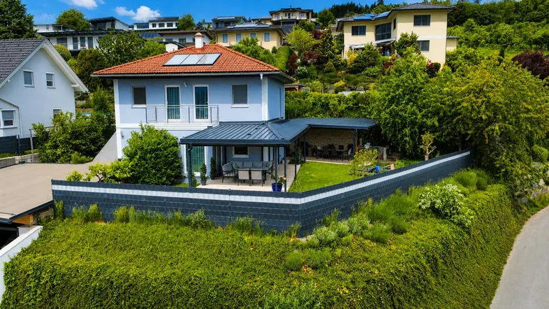 Haus mit überdachter Terrasse, Garten und Blick auf die umliegende Hügellandschaft.