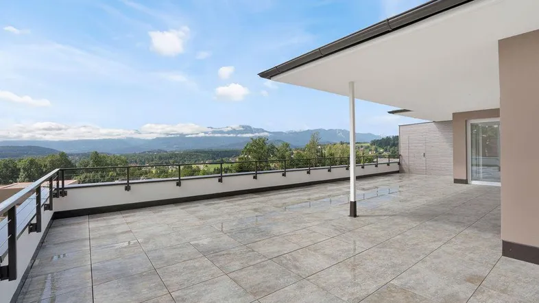 Große, geflieste Terrasse mit weitem Blick auf die umliegende Landschaft und Berge.
