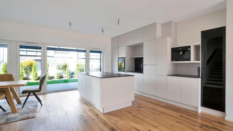 Moderne offene Küche mit Kochinsel, Essbereich und Zugang zum Garten, ausgestattet mit Holzboden.