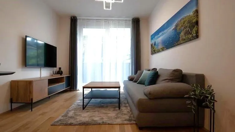 Helles Wohnzimmer mit modernem Sofa, Fernseher und Holzboden, ideal zum Entspannen.