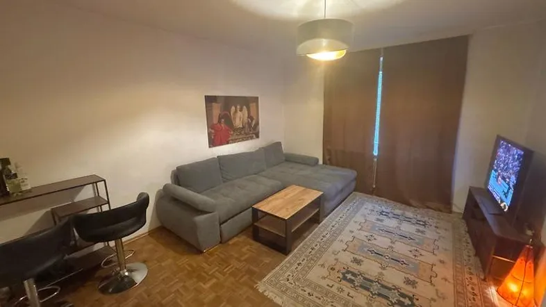 Gemütliches Wohnzimmer mit großem Ecksofa, Fernseher und einer kleinen Bar-Ecke.