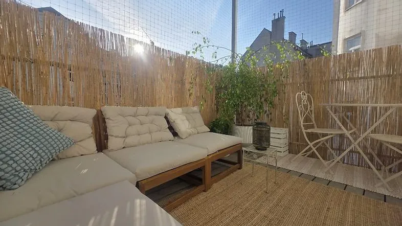 Gemütliche Terrasse mit bequemen Sitzmöbeln, Bambusverkleidung und viel Sonnenlicht.