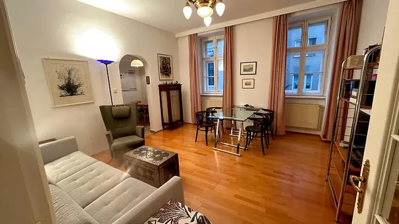 Geräumiges Wohn-Esszimmer mit Holzboden, gemütlicher Sitzecke und Esstisch am Fenster.