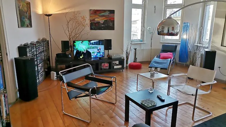 Geräumiges Wohnzimmer mit Holzboden, modernen Möbeln und Unterhaltungselektronik.