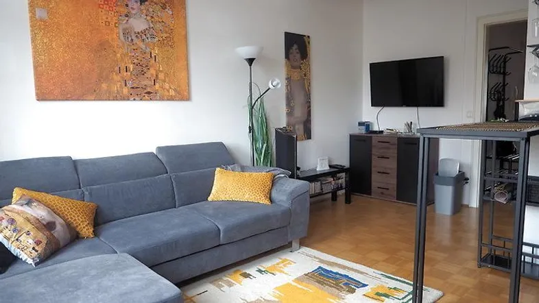 Gemütliches Wohnzimmer mit großem Ecksofa, Holzboden und moderner Kunst an den Wänden.
