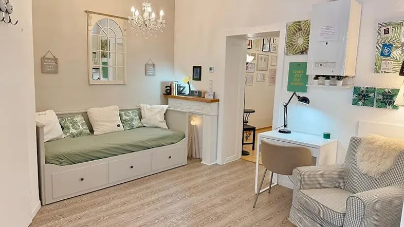 Helles Wohnzimmer mit Tagesbett, Schreibtisch und dekorativem Kamin in modernem Stil.