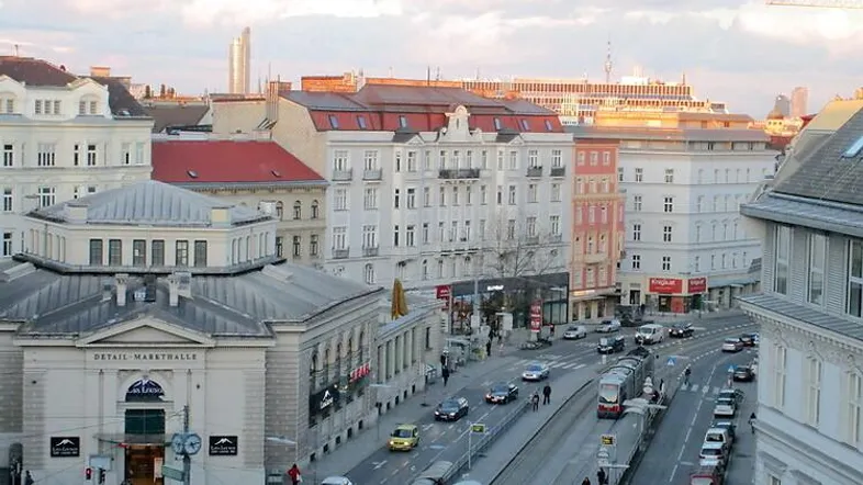 Panoramablick über eine belebte Stadtstraße mit historischen Gebäuden und Straßenbahnverkehr.