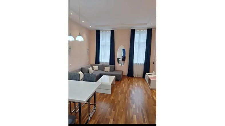 Heller Wohn- und Essbereich mit bequemer Couch, Esstisch und Holzboden.