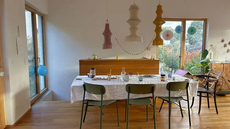 Heller Essbereich mit Holzboden, großen Fenstern und dekorativen Hängelampen, ideal für gesellige Runden.