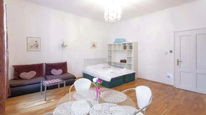 Heller Raum mit Bett, Sofa und Esstisch, ideal als kombinierter Wohn- und Schlafbereich.