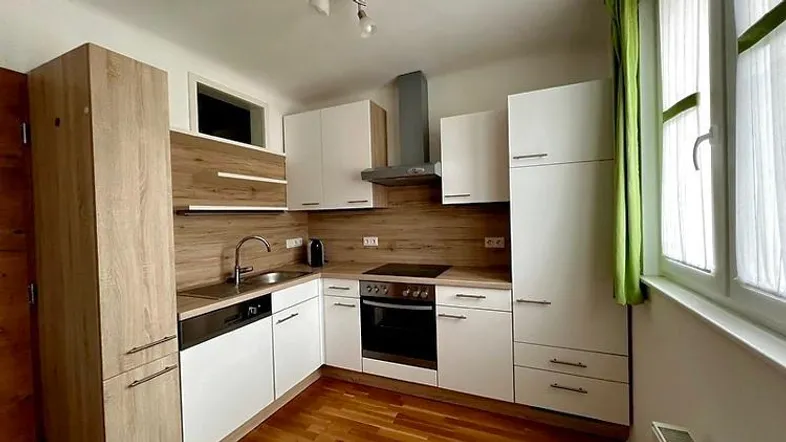 Moderne Küche mit weißen Schränken, Holzoptik-Akzenten und integrierten Geräten.
