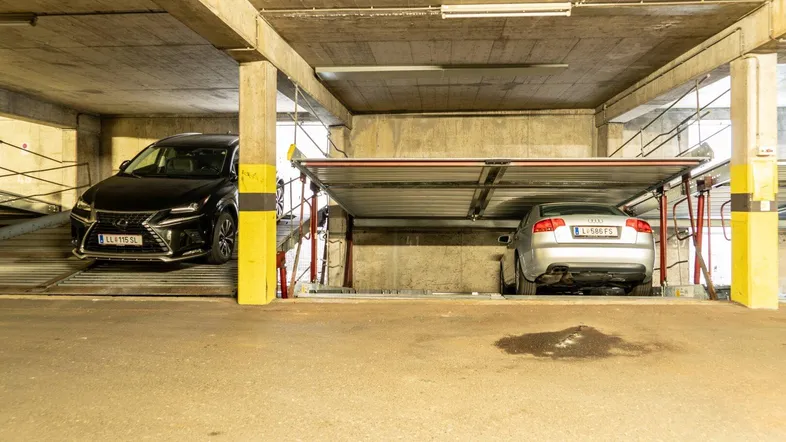 Tiefgarage mit Doppelparker-System und zwei geparkten Fahrzeugen in einer modernen Anlage.