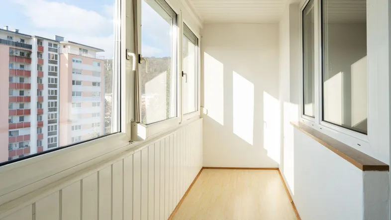 Heller, verglaster Balkon mit Blick auf die umliegenden Gebäude und viel Tageslicht.