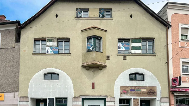 Historisches Gebäude mit traditioneller Fassade, Erker und Schaufenstern im Erdgeschoss an der Straße.