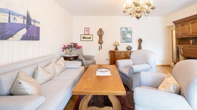 Gemütliches Wohnzimmer mit traditionellen Möbeln, Kronleuchter und Parkettboden.