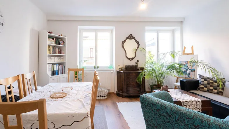 Helles Wohn- und Esszimmer mit Holzboden, großem Esstisch und gemütlicher Sitzecke.