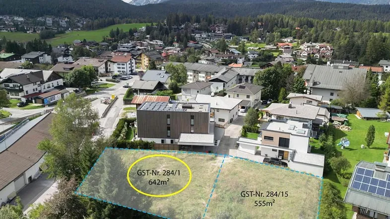 Luftaufnahme eines Wohngebiets mit Bergblick und zwei markierten Baugrundstücken.