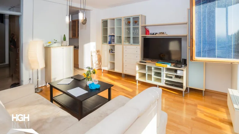 Helles Wohnzimmer mit Parkettboden, beigem Sofa und Blick in die offene Küche.
