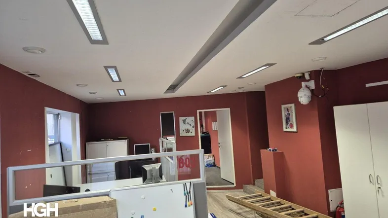 Geräumiges Büro mit roten Wänden, modernen Deckenleuchten und Arbeitsplätzen.