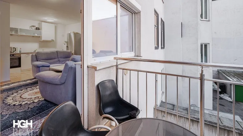 Kleiner Balkon mit Sitzgelegenheiten und Blick in den Wohnbereich durch die Balkontür.