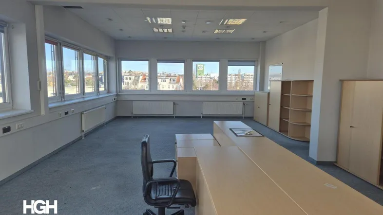 Geräumiges Büro mit Teppichboden, großen Fenstern und Blick auf die Stadt, ausgestattet mit Büromöbeln.