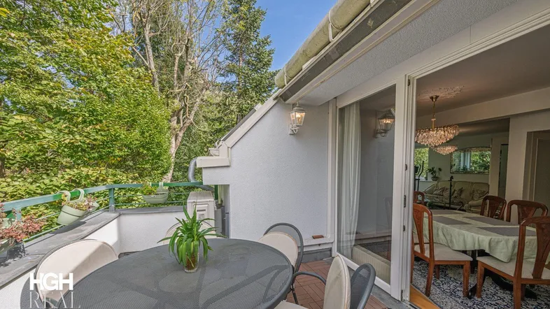 Geräumige Terrasse mit Esstisch und Stühlen, umgeben von viel Grün, mit direktem Zugang zum eleganten Essbereich.