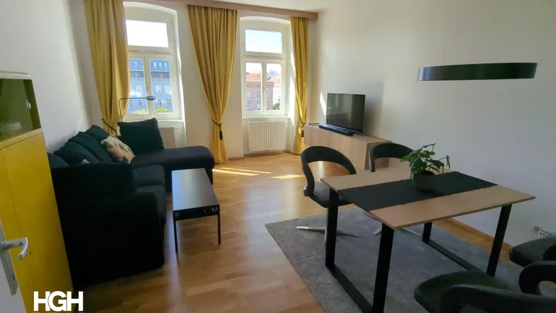 Helles Wohn- und Esszimmer mit Parkettboden, bequemer Sitzecke und Esstisch für gesellige Stunden.