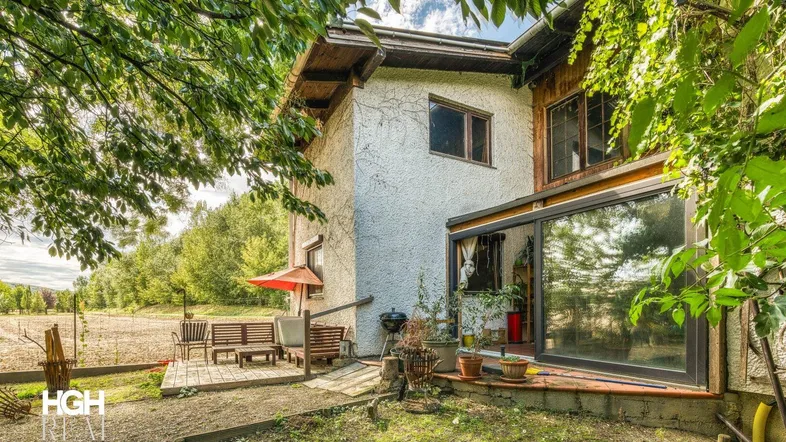 Außenansicht des Hauses mit einer möblierten Terrasse und Blick ins Grüne.