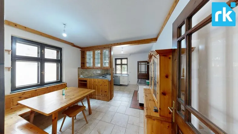 Geräumige Küche mit traditionellen Holzmöbeln, Essbereich und gefliestem Boden.