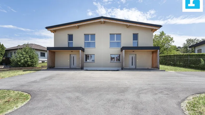 Moderne Doppelhaushälfte mit heller Fassade und zwei Eingängen unter einem Vordach.