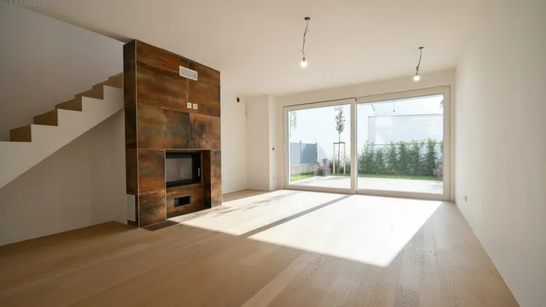 Helles Wohnzimmer mit modernem Kamin, Holzboden und Zugang zum Garten.