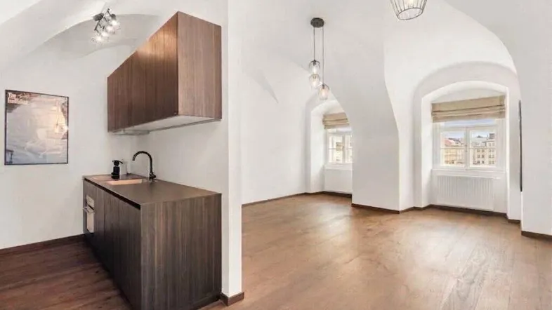 Heller Wohnbereich mit Gewölbedecke, Holzboden und integrierter Küchenzeile sowie Stadtblick.