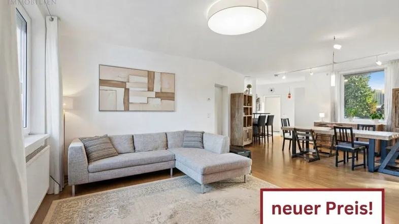 Helles, offenes Wohn- und Esszimmer mit Parkettboden, bequemer Couch und großem Esstisch.