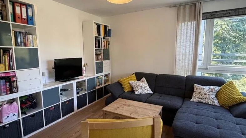 Helles Wohnzimmer mit Holzboden, großem Sofa und Bücherregalen, bietet viel Platz zum Entspannen.