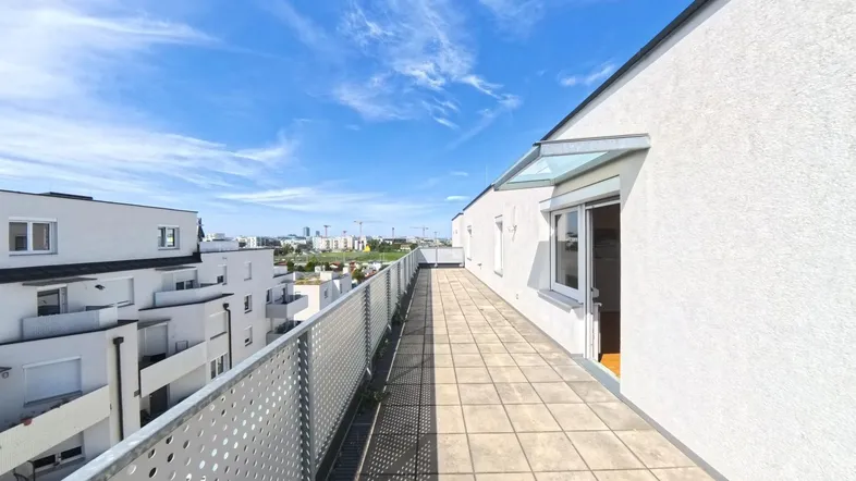 Lange, geflieste Terrasse mit Metallgeländer und weitem Blick über die Umgebung.