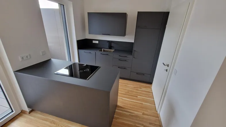Moderne Küche in Grau mit Kochinsel, Induktionskochfeld und integrierten Geräten, ideal für den Erstbezug.