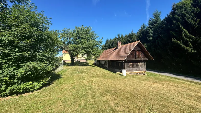 Rustikales Holzhaus auf einem grünen Hügel mit Blick auf die umliegende Landschaft.