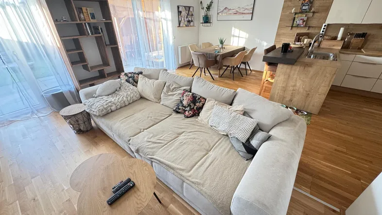 Helles, offenes Wohnzimmer mit großem Sofa, Essbereich und integrierter Küche.