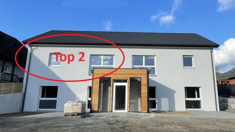 Modernes Neubaugebäude mit heller Fassade und großen Fenstern unter blauem Himmel.