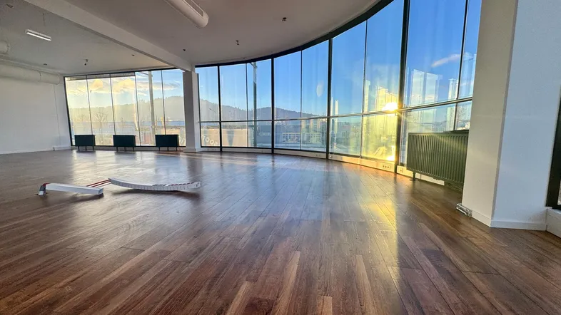 Helles, offenes Zimmer mit großen, gebogenen Fenstern und Holzboden, bietet weite Aussicht.