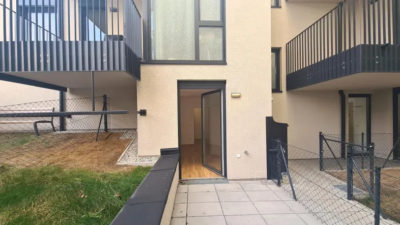 Kleine Terrasse mit Zugang zum Gartenbereich und Blick auf die modernen Balkone des Gebäudes.