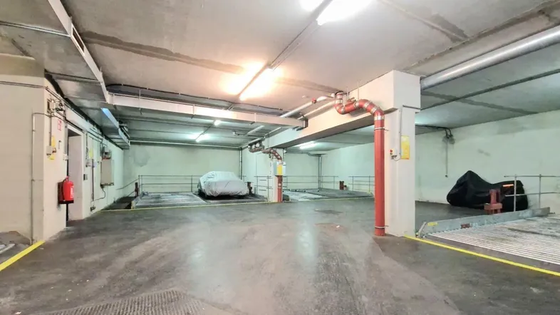 Geräumige Tiefgarage mit Betonwänden und -decken, ausgestattet mit Parklifts für mehrere Fahrzeuge.