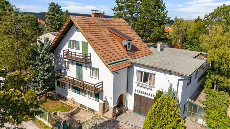 Traditionelles Haus mit mehreren Balkonen und rotem Ziegeldach, umgeben von viel Grün.