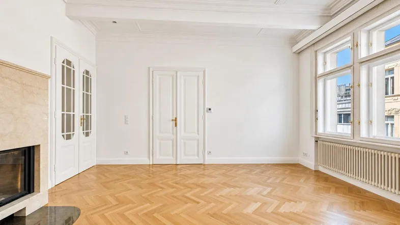 Helles Wohnzimmer mit Fischgrätparkett, dekorativer Decke und Kamin, ideal für gemütliche Stunden.