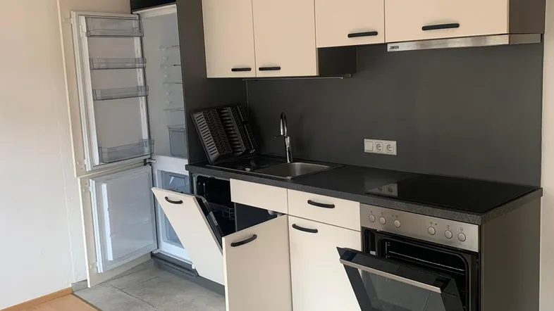 Moderne Einbauküche mit hellen Fronten, integrierten Geräten und praktischem Fliesenboden.