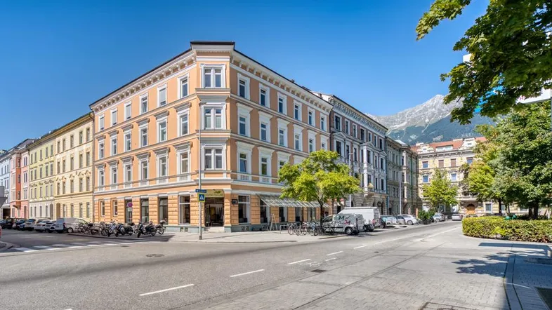Historisches Eckgebäude mit traditioneller Architektur und Blick auf die umliegende Stadt und Berge.